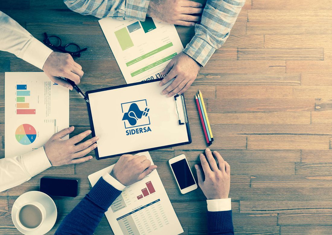 Reunião de trabalho com relatórios e uma prancheta com o logo da Sidersa